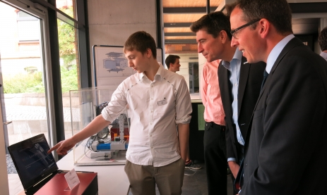 Ein Schüler präsentiert sein Gesellenstück dem Schulleiter Thomas Ettwein und dem Landrat Sven Hinterseh
