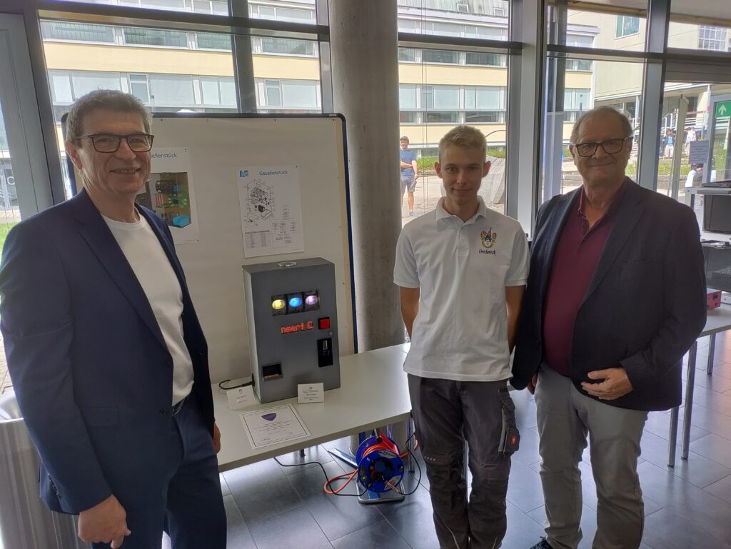 Oberbürgermeister Eugen Roth und Schulleiter Thomas Ettwein lassen sich von Frederick Baur sein Gesellenstück Slotmachine erklären