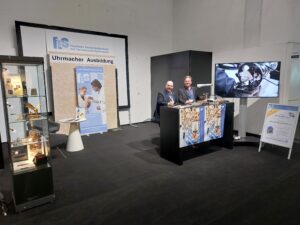 Die Uhrmacher-Lehrer Alexander Loga (rechts) und Rolf Herrmann präsentieren sich auf einem Stand der Uhrenmesse Inhorgenta.