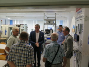 Schulleiter Thomas Ettwein mit Landrat Sven Hinterseh und Fachlehrer Michael Miksic an der Industrie 4.0 Lernfabrik