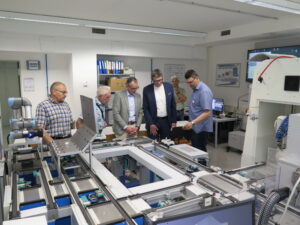 Schulleiter Thomas Ettwein mit Landrat Sven Hinterseh und Fachlehrer Michael Miksic an der Industrie 4.0 Lernfabrik